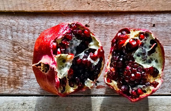 Torn pomegranate on a wooden surface.