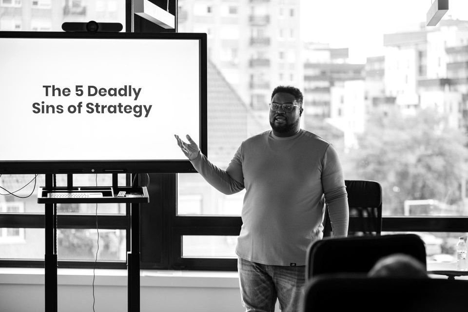 Adam Thomas presenting The 5 Deadly Sins of Strategy to a room of product people