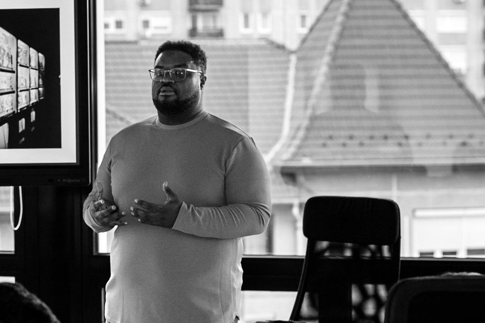 Adam Thomas mid-explanation beside a screen in a workshop room
