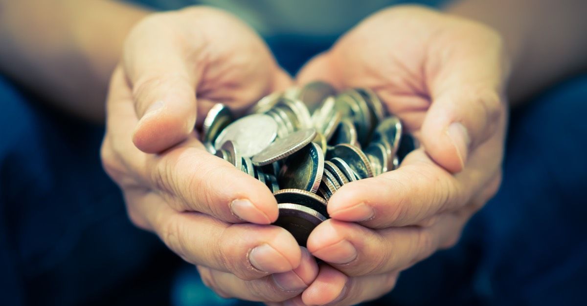Two hands shaped like a heart, holding a bunch of silver coins