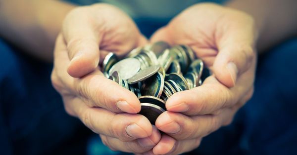 Two hands shaped like a heart, holding a bunch of silver coins