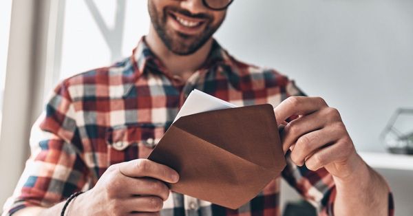 A smiling man looking down at the contents of an envelope he has opened