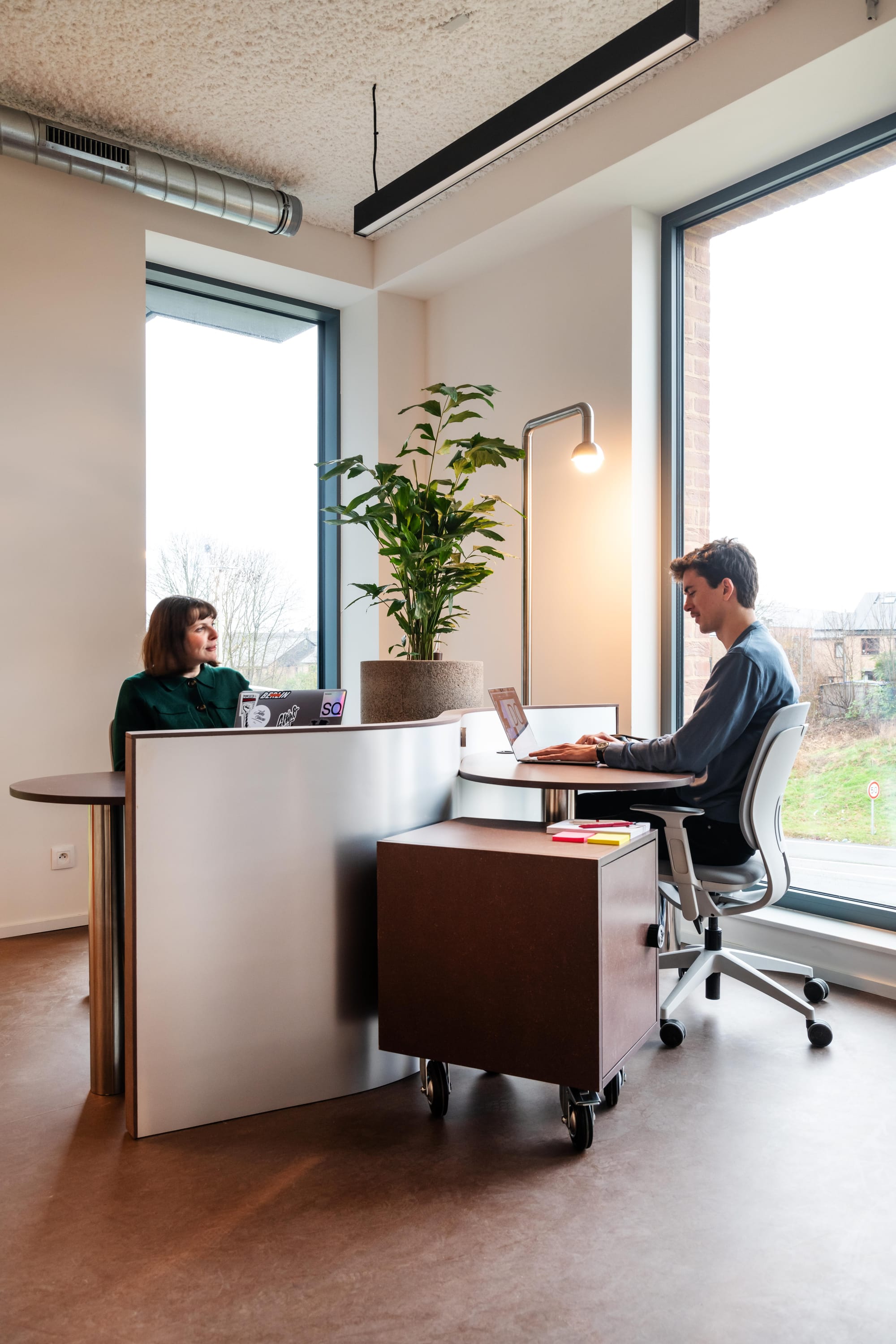 Silversquare Co-Working Space by Lilian van Daal. Photography by Marthe Hoet. Two people co-working in a bright office with outside views.