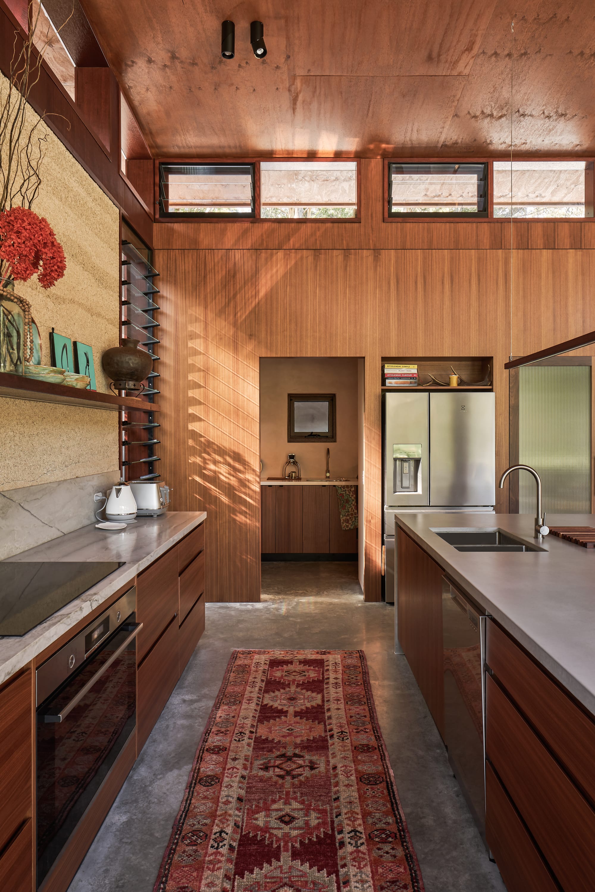 Modern tropical, interior design kitchen with wooden and hempcrete walls and middle eastern long carpet in earthy hues.