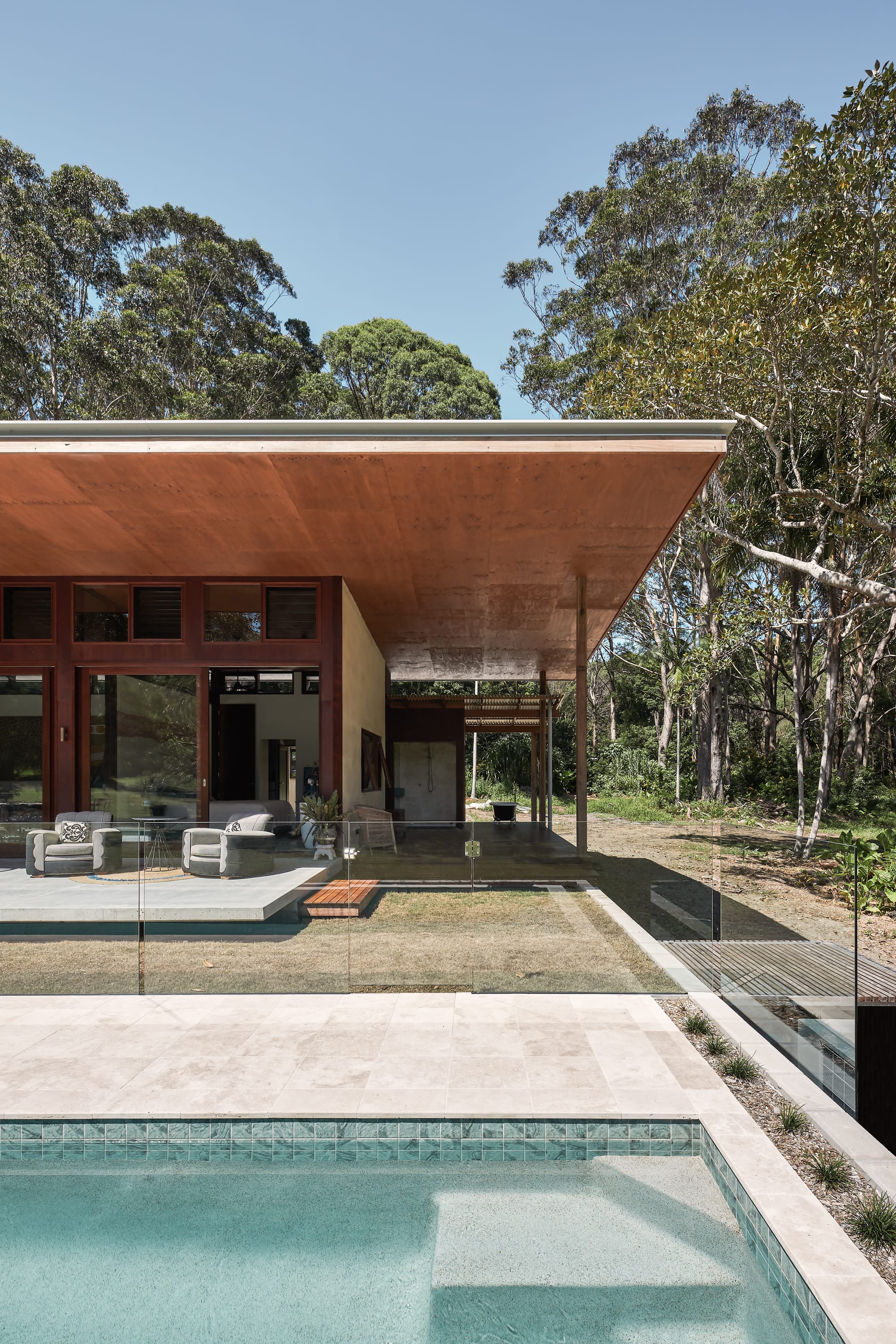 Outside view on modern tropical family home with wooden facade and flat roof.