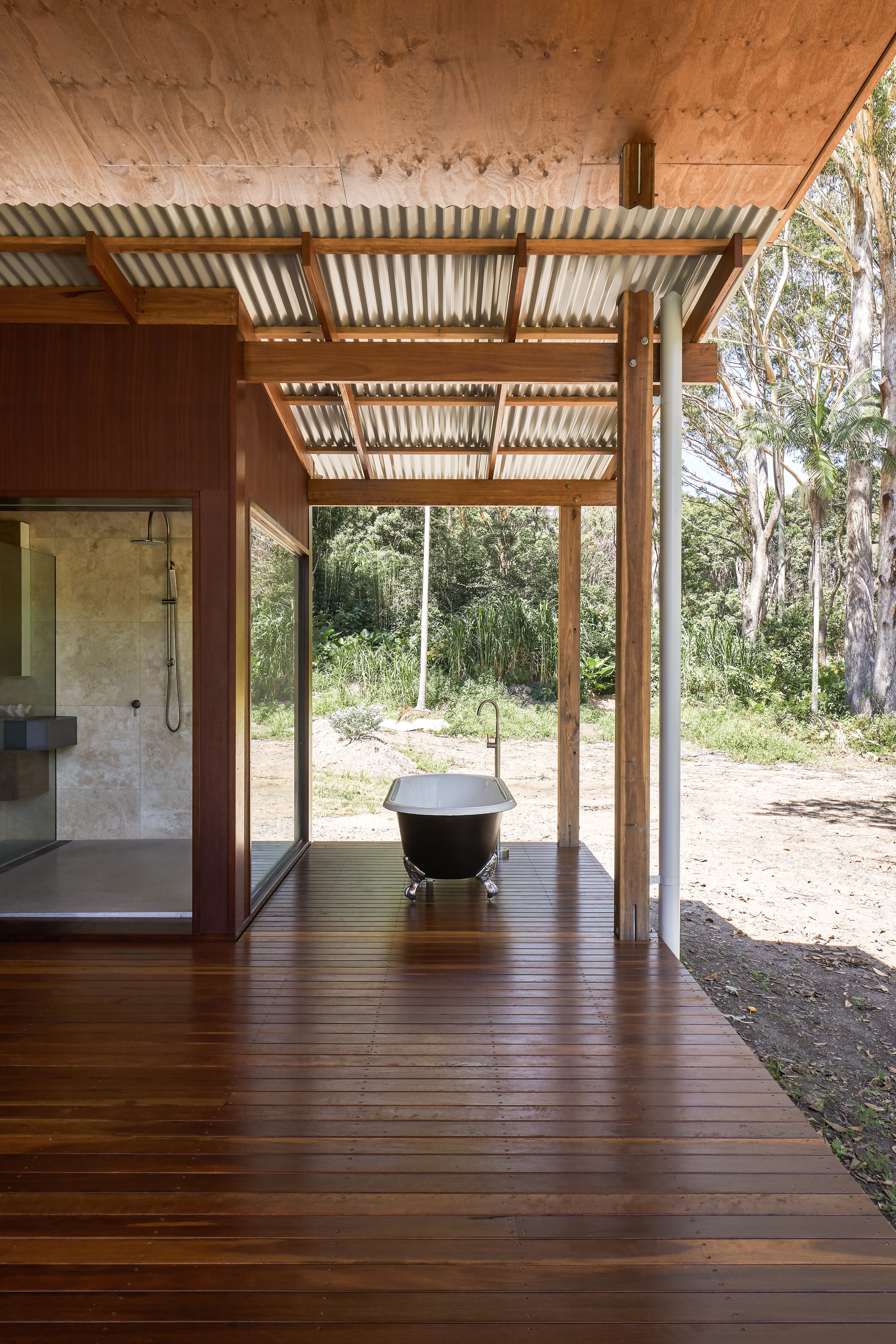 Wooden walkway to outside, glassed shower and free standing, open bathtub.