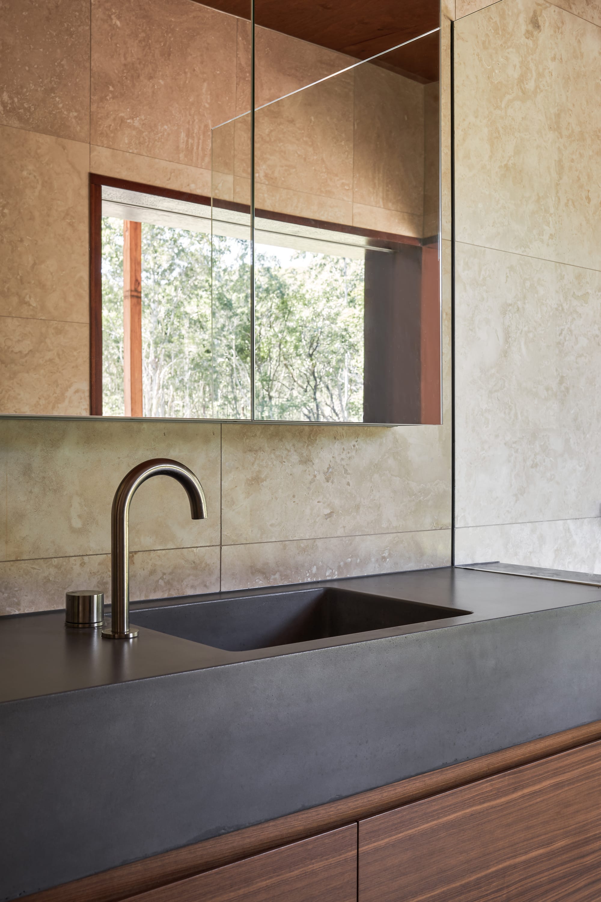 Modern bathroom sink with natural stone wall and minimalist fixtures.