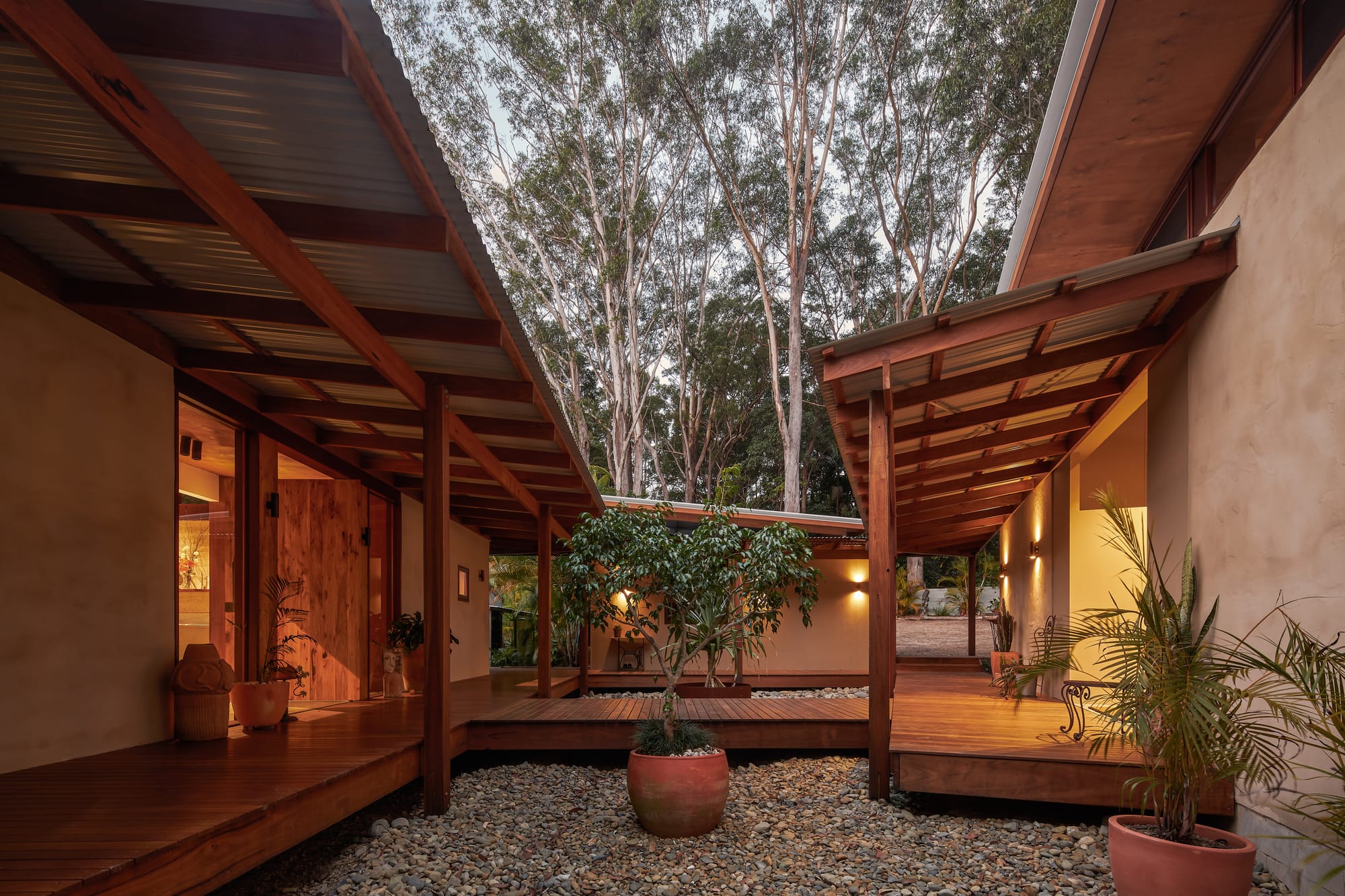 Courtyard with wooden walkway, soft, warm light and surrounding nature.