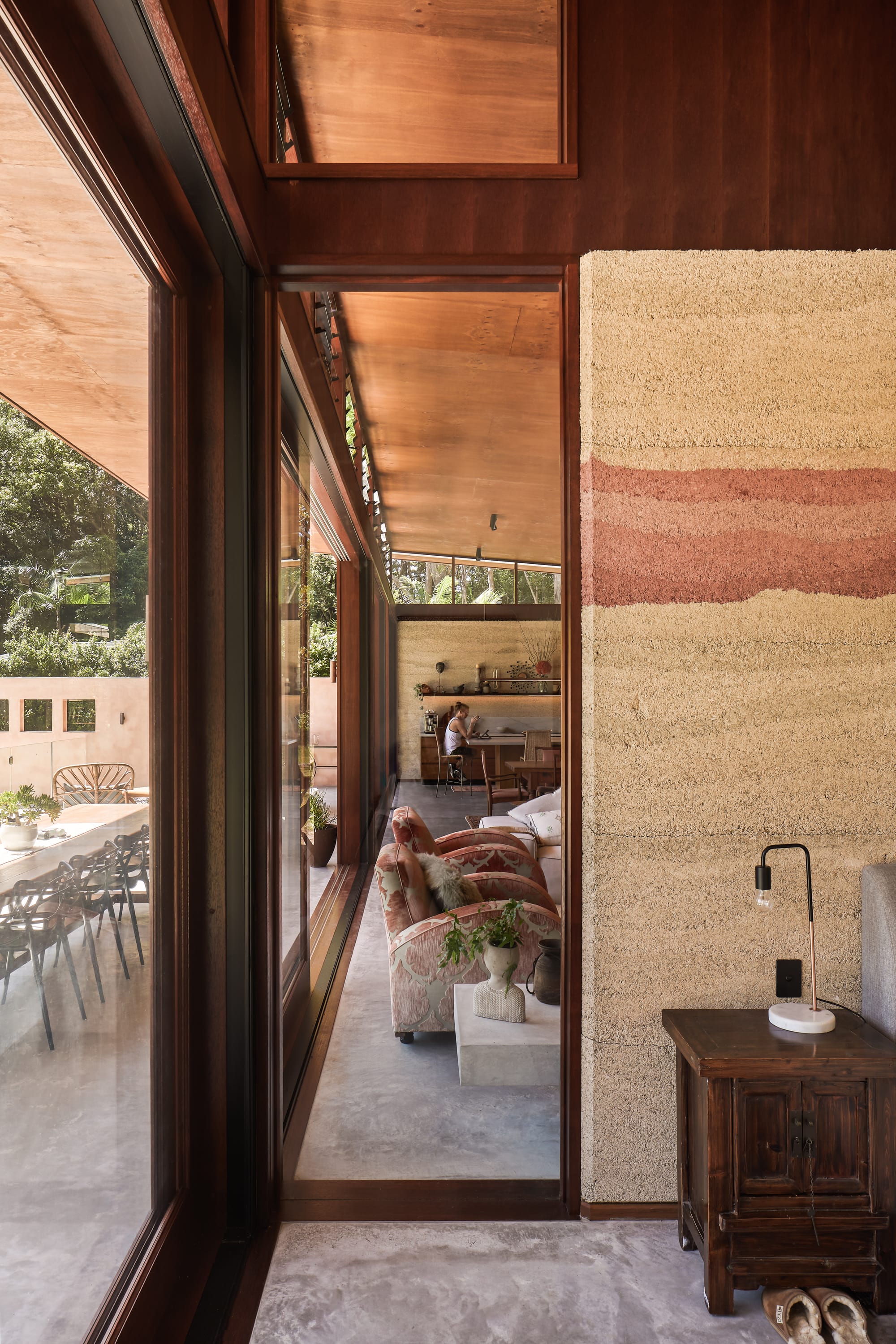 View to modern, glassed interior and exterior with hempcrete wall and glassed, wooden framed slide doors.