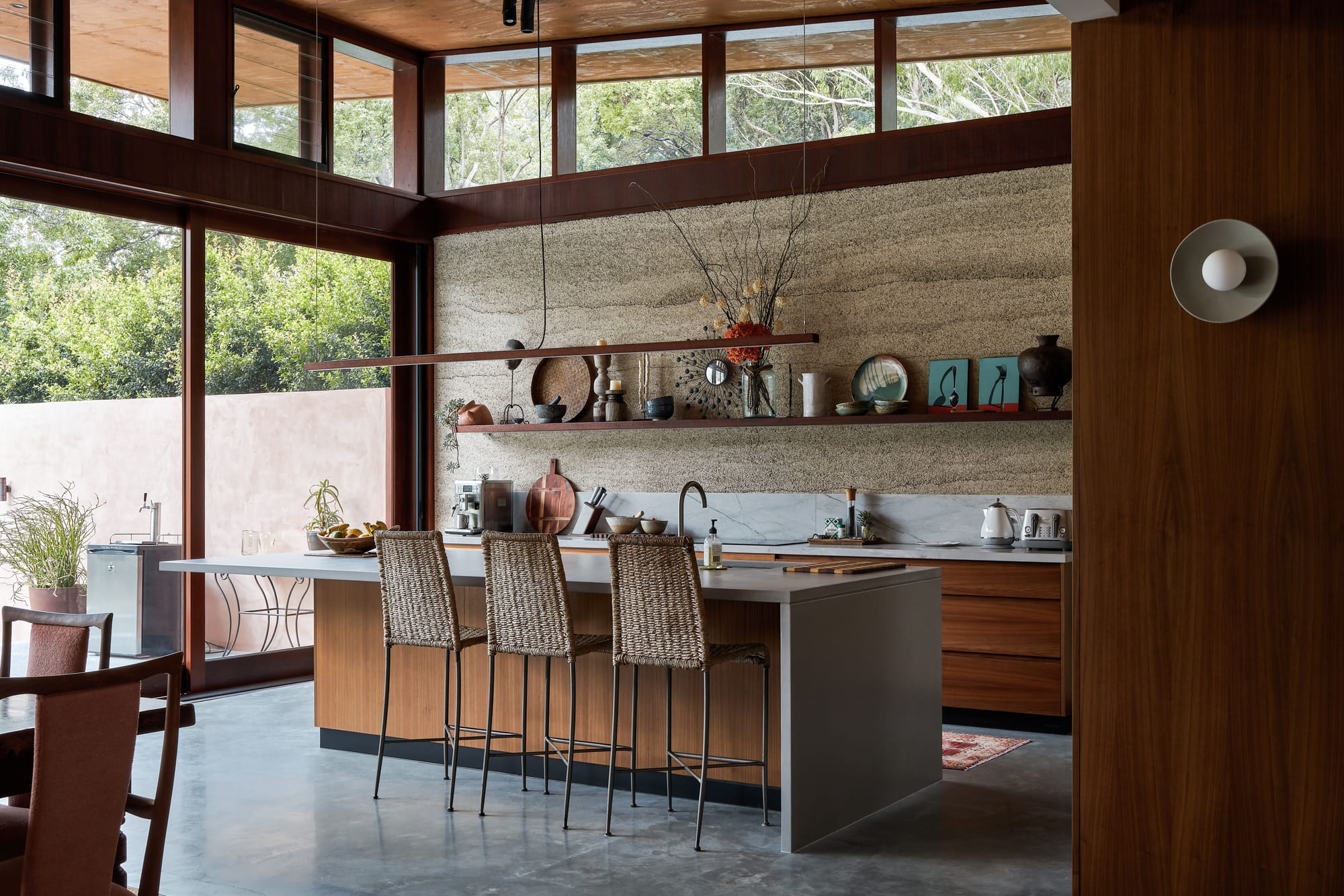Modern interior architecture kitchen with rattan high chairs and hempcrete wall in earthy hues.