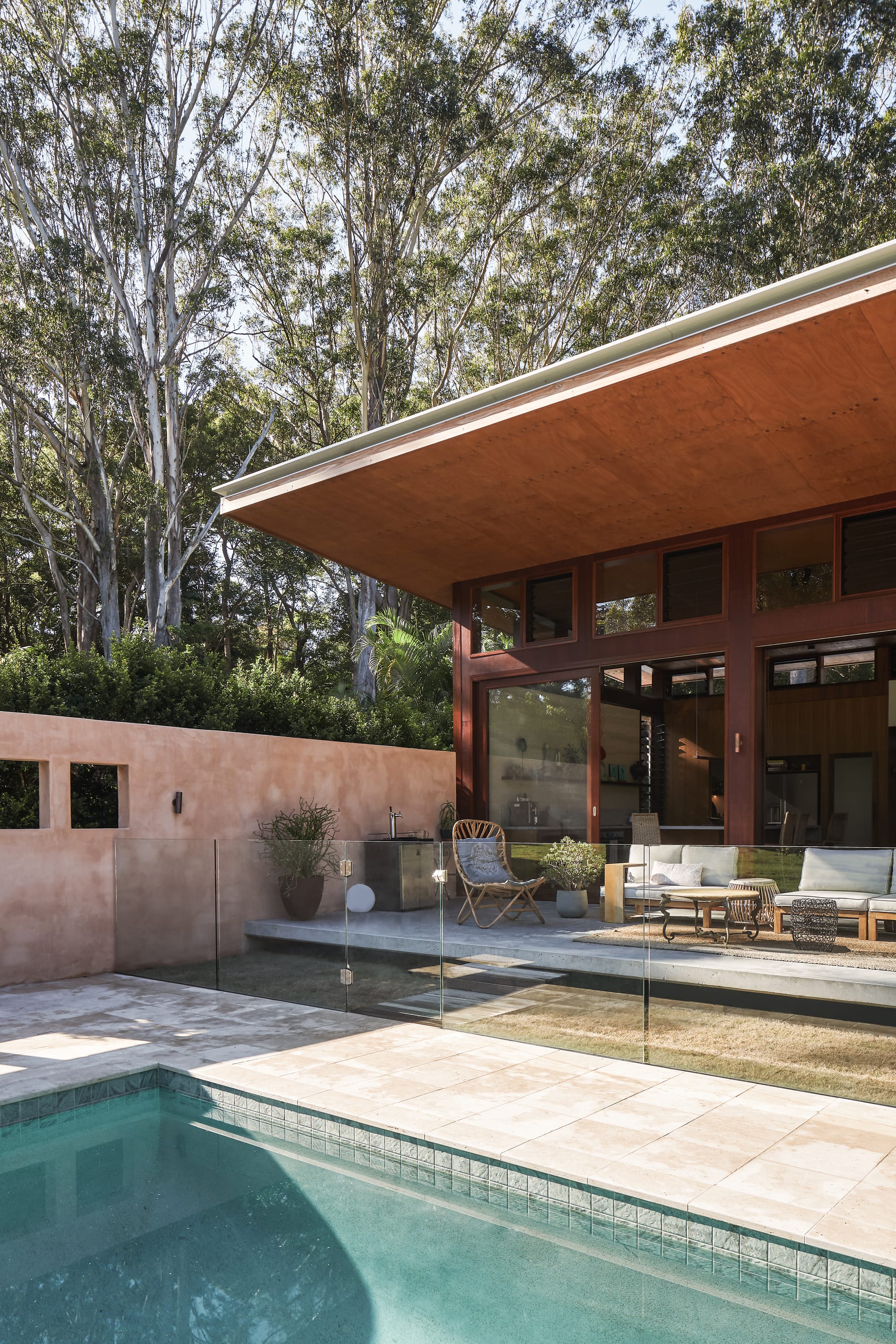 Modern, tropical architecture outside view with pool, wooden facade and terracotta painted wall.