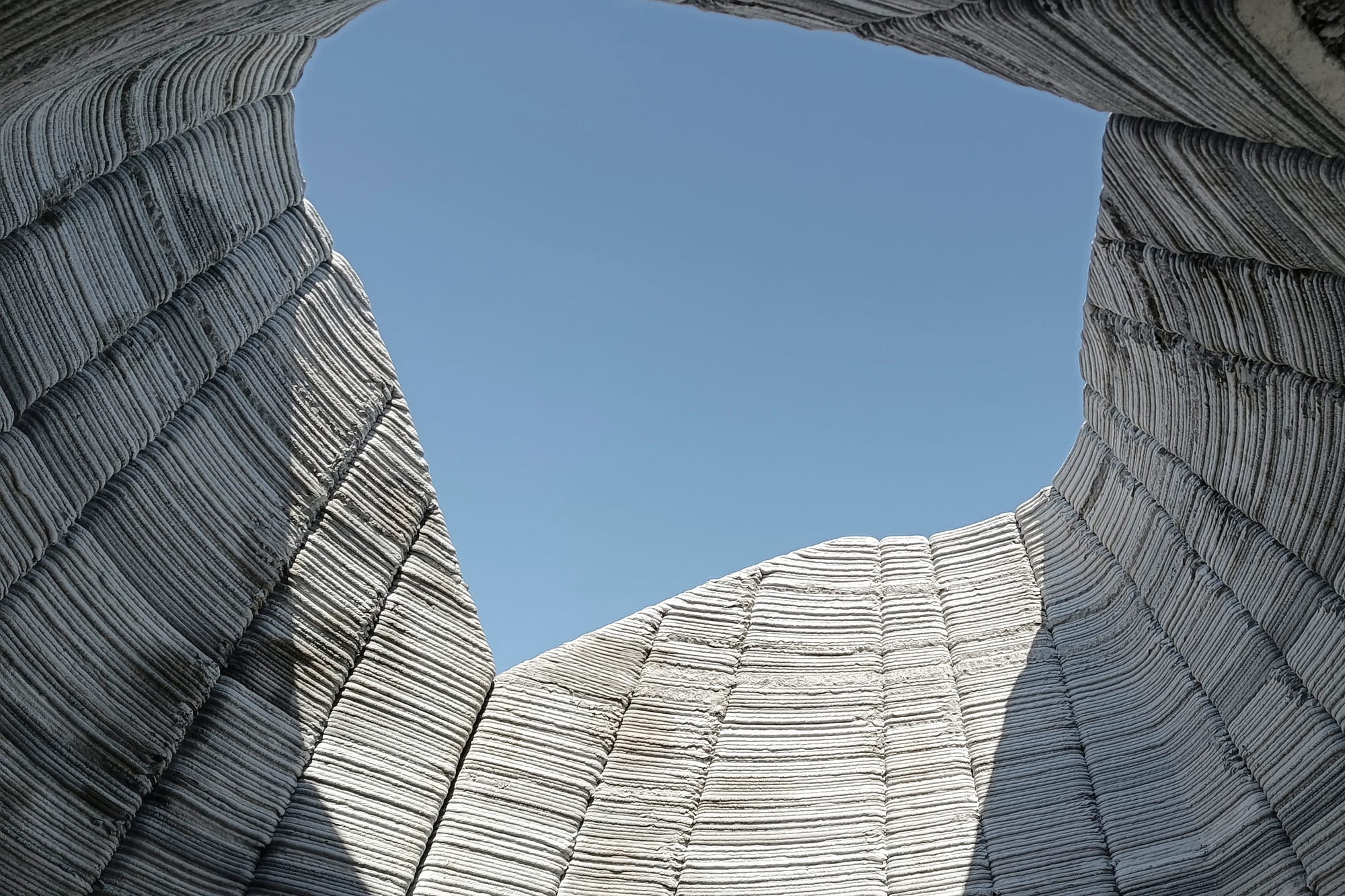 3D printed concrete capsule home under construction, with roof light.