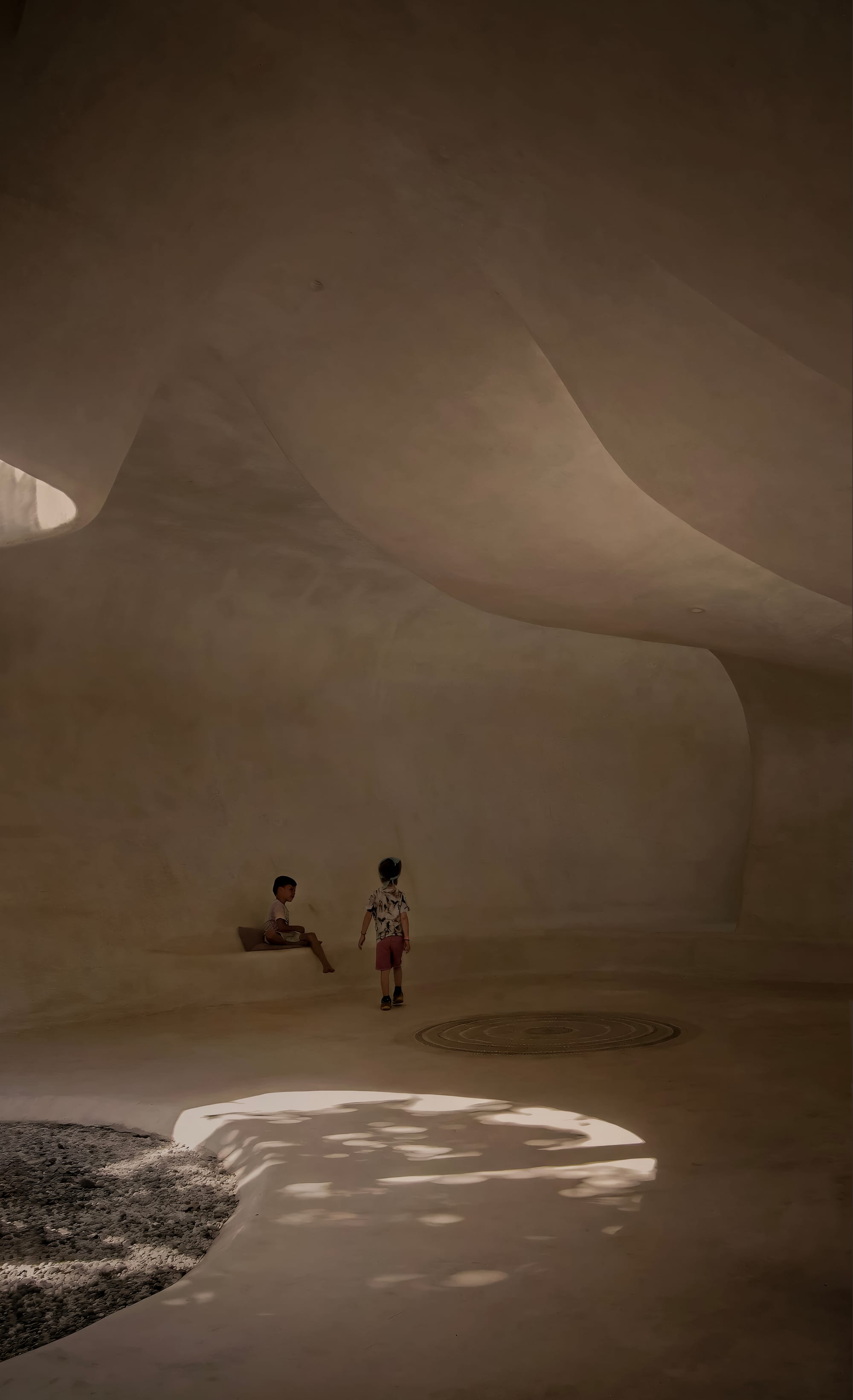 Kids playing in organic shaped interior, with high ceilings and Tadelakt finish.
