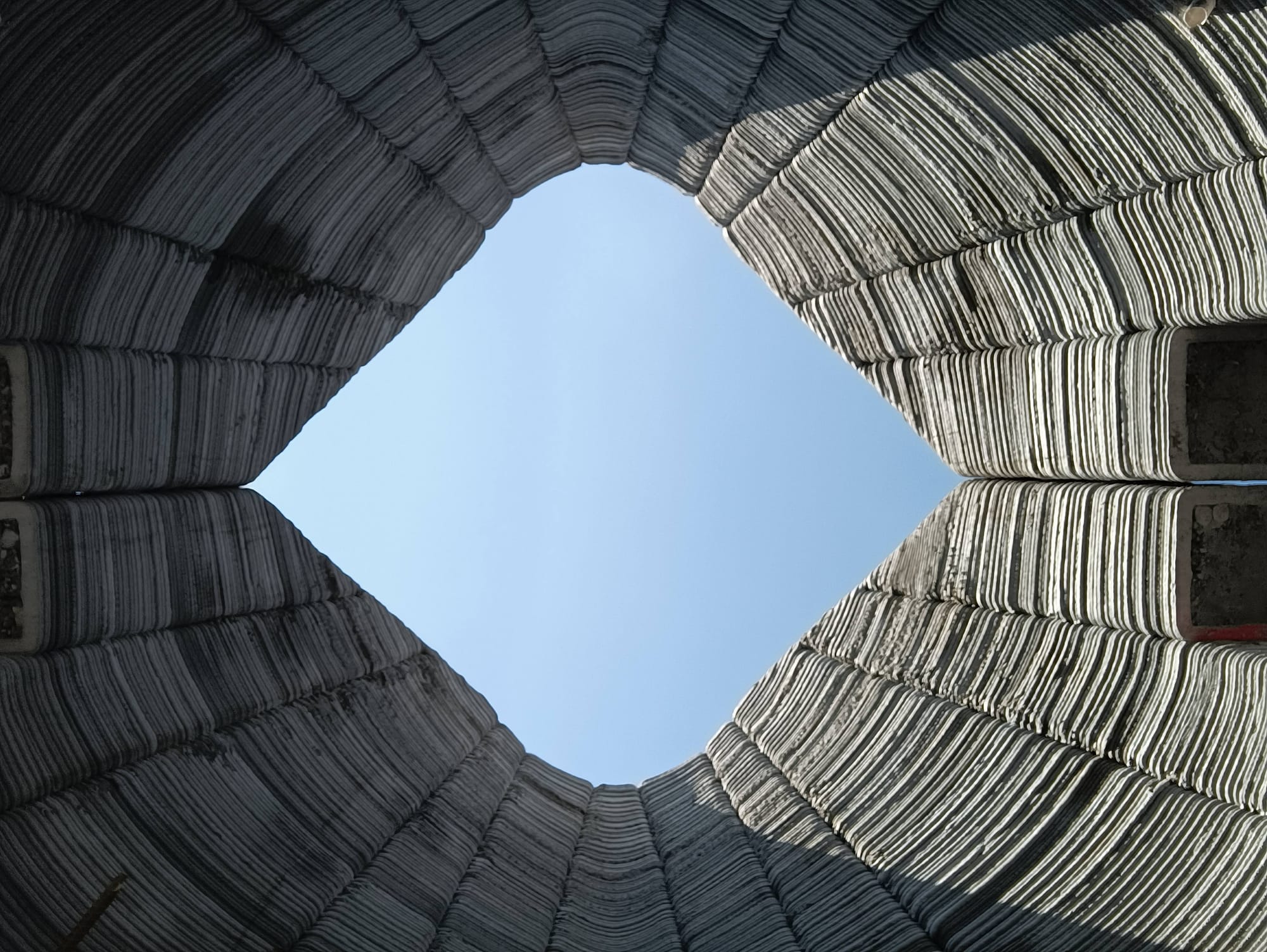 3D printed concrete capsule home under construction, with roof light.
