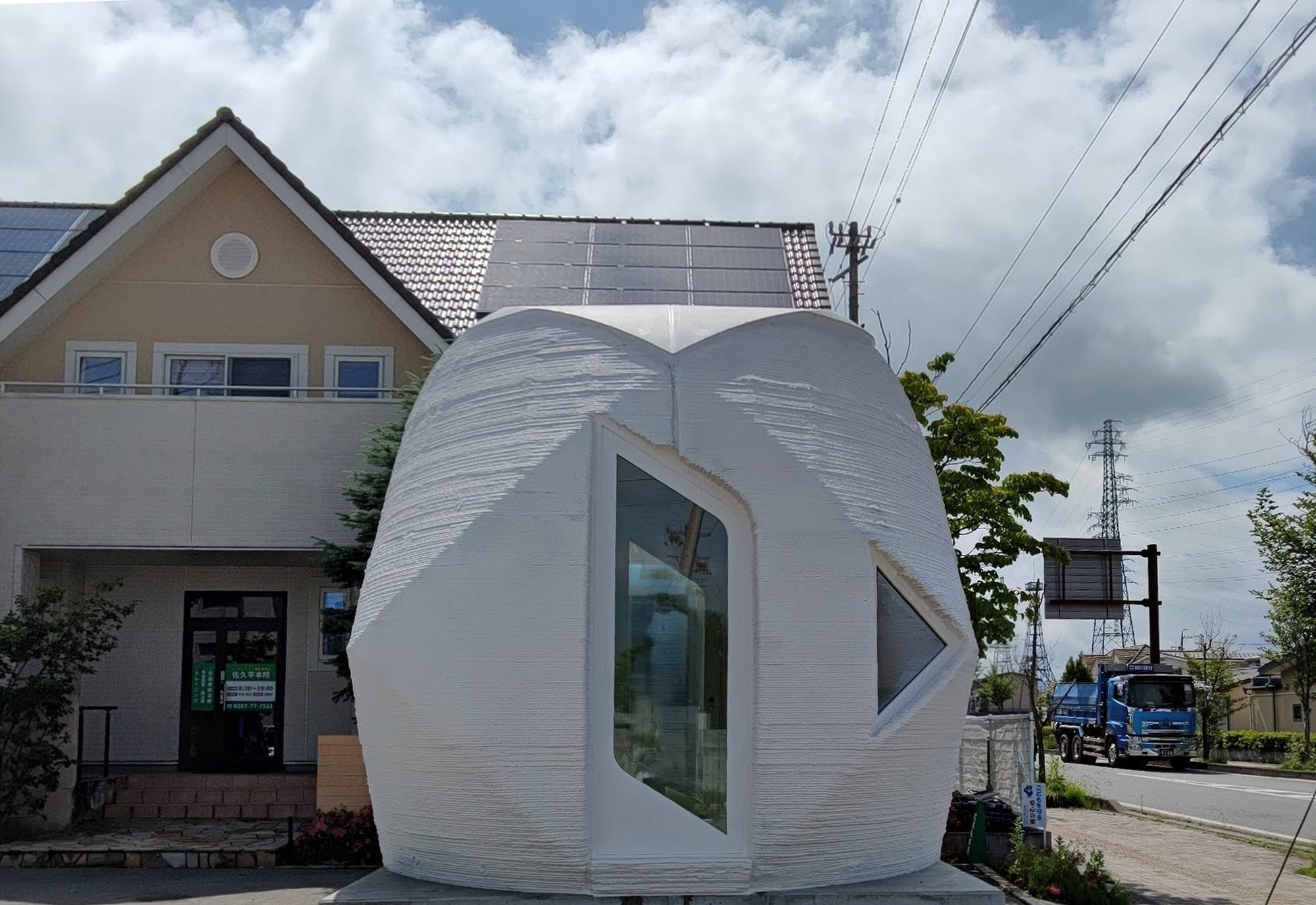 3D printed cylindric shaped, futuristic concrete home in suburban area.