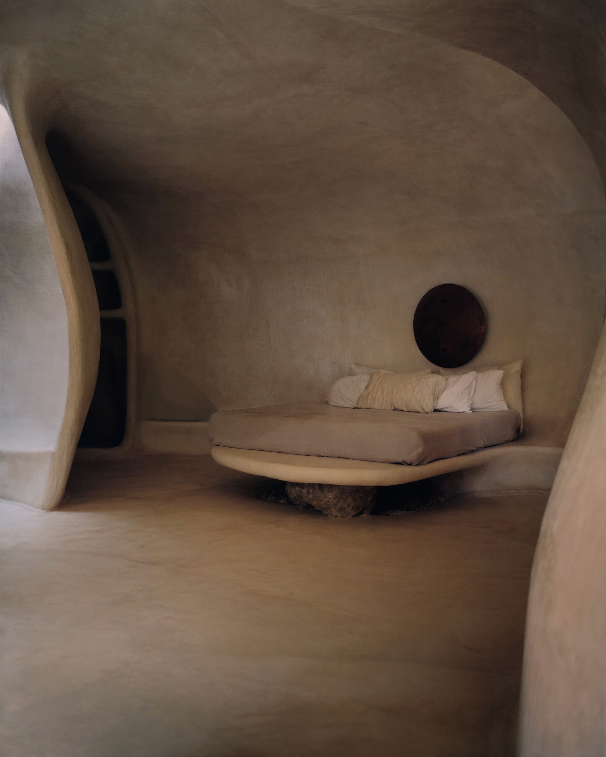 Organically shaped interior bedroom with seamlessly integrated bed in warm hues.