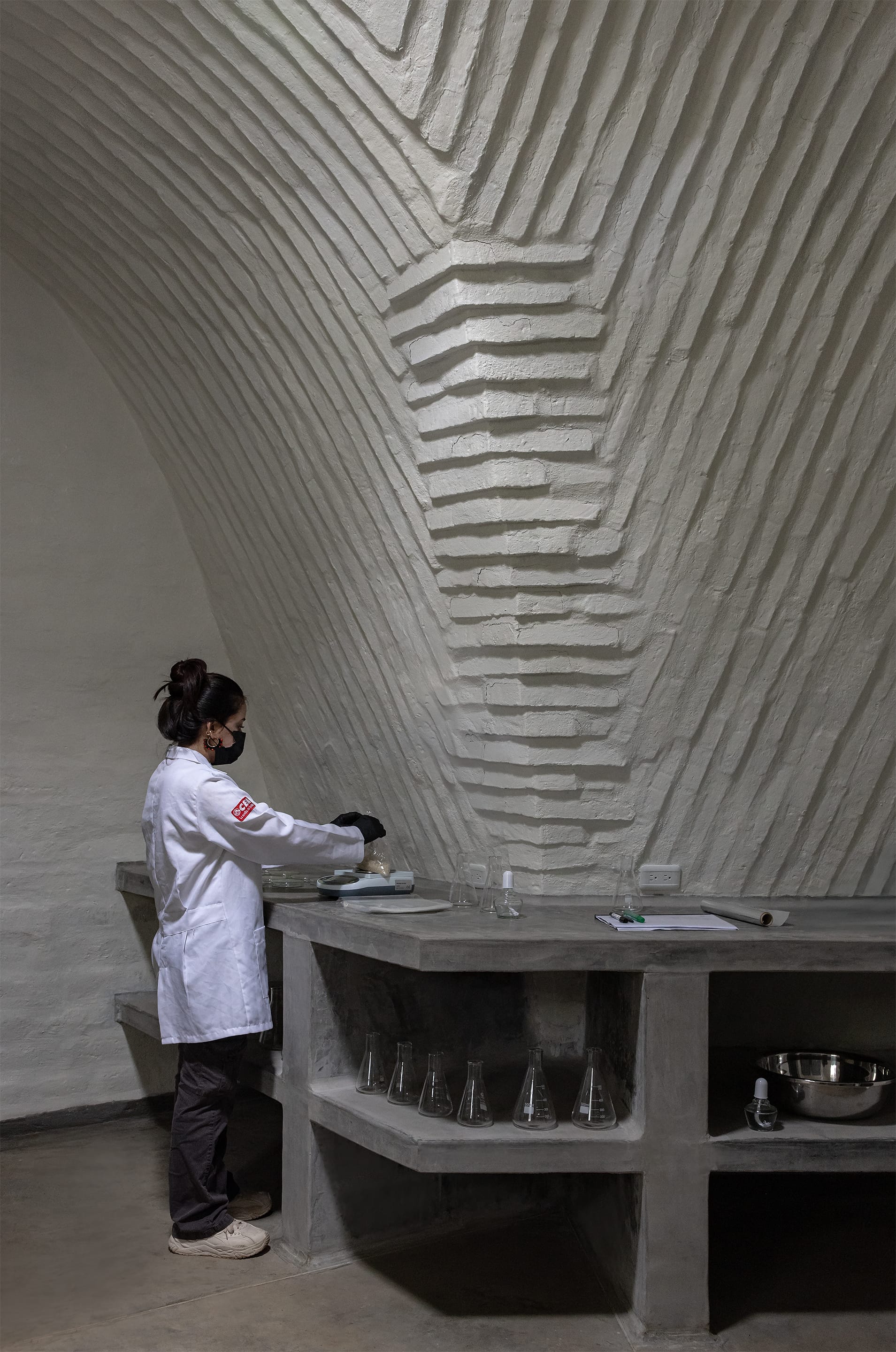 Woman working in brick constructed and layered, white laboratory with concrete work bases.
