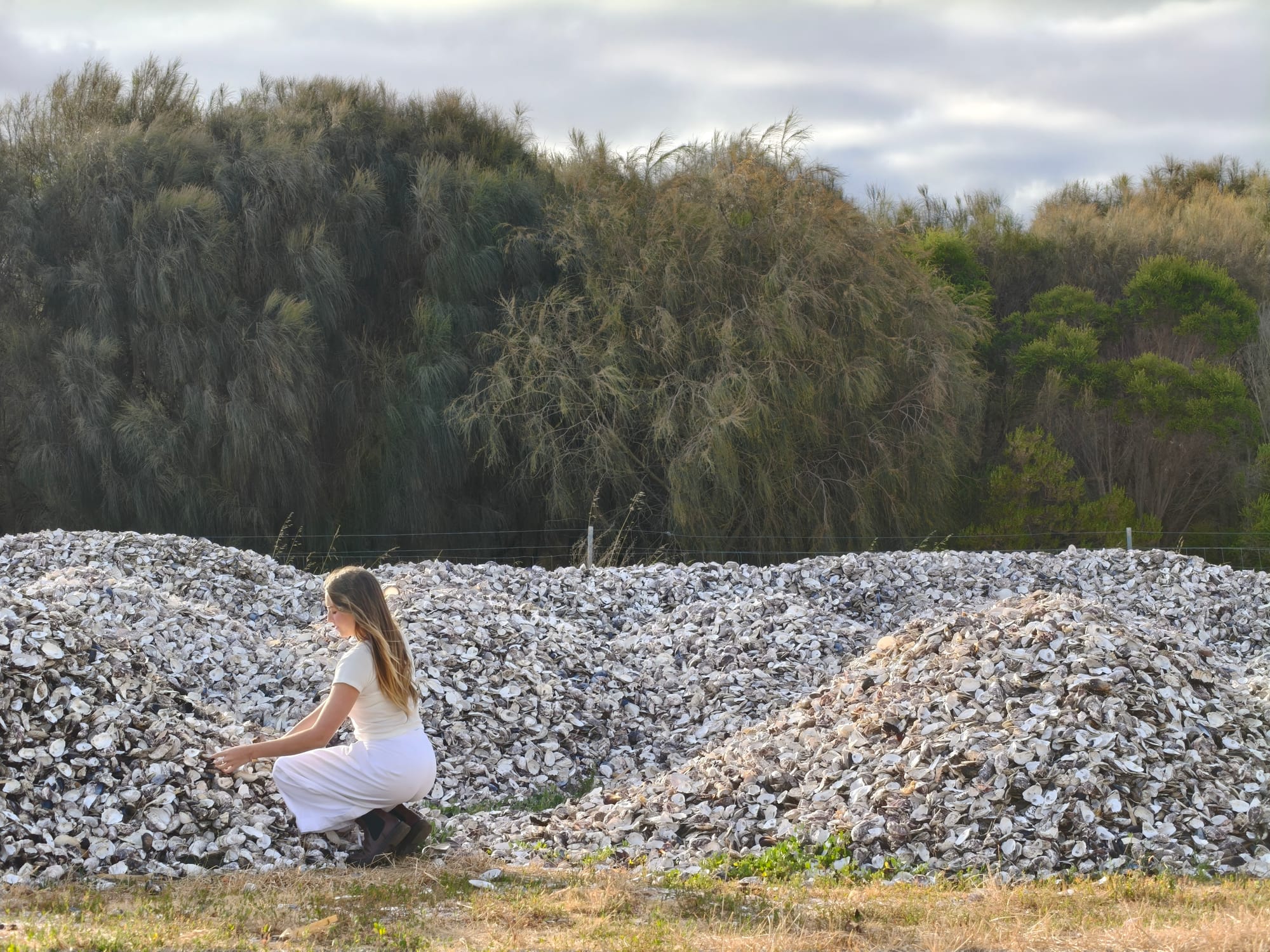 Woman looking at mountains of seashell waste.