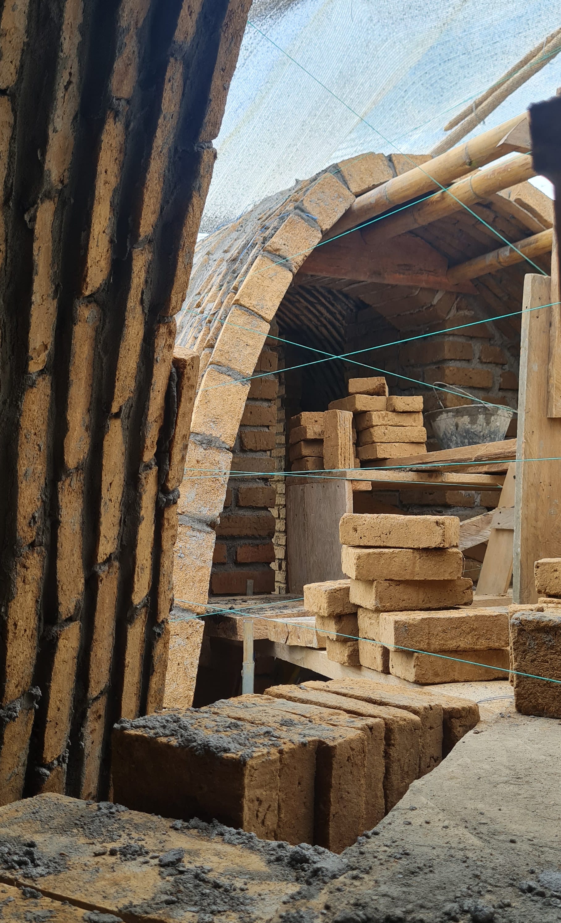 Construction site with bamboo supported arches and earth bricks.