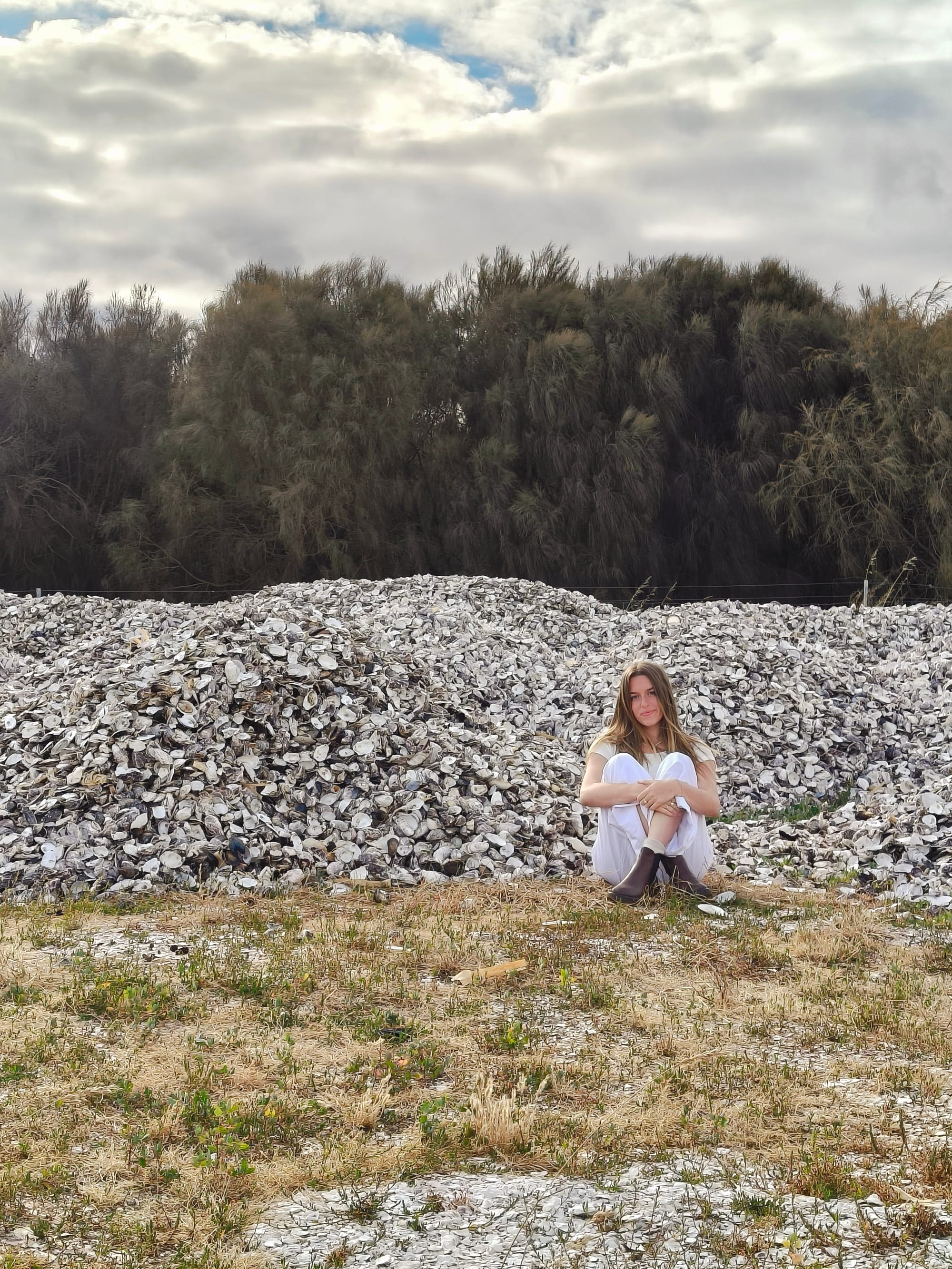 Chloe Harper sitting next to a mountain of sea shells.