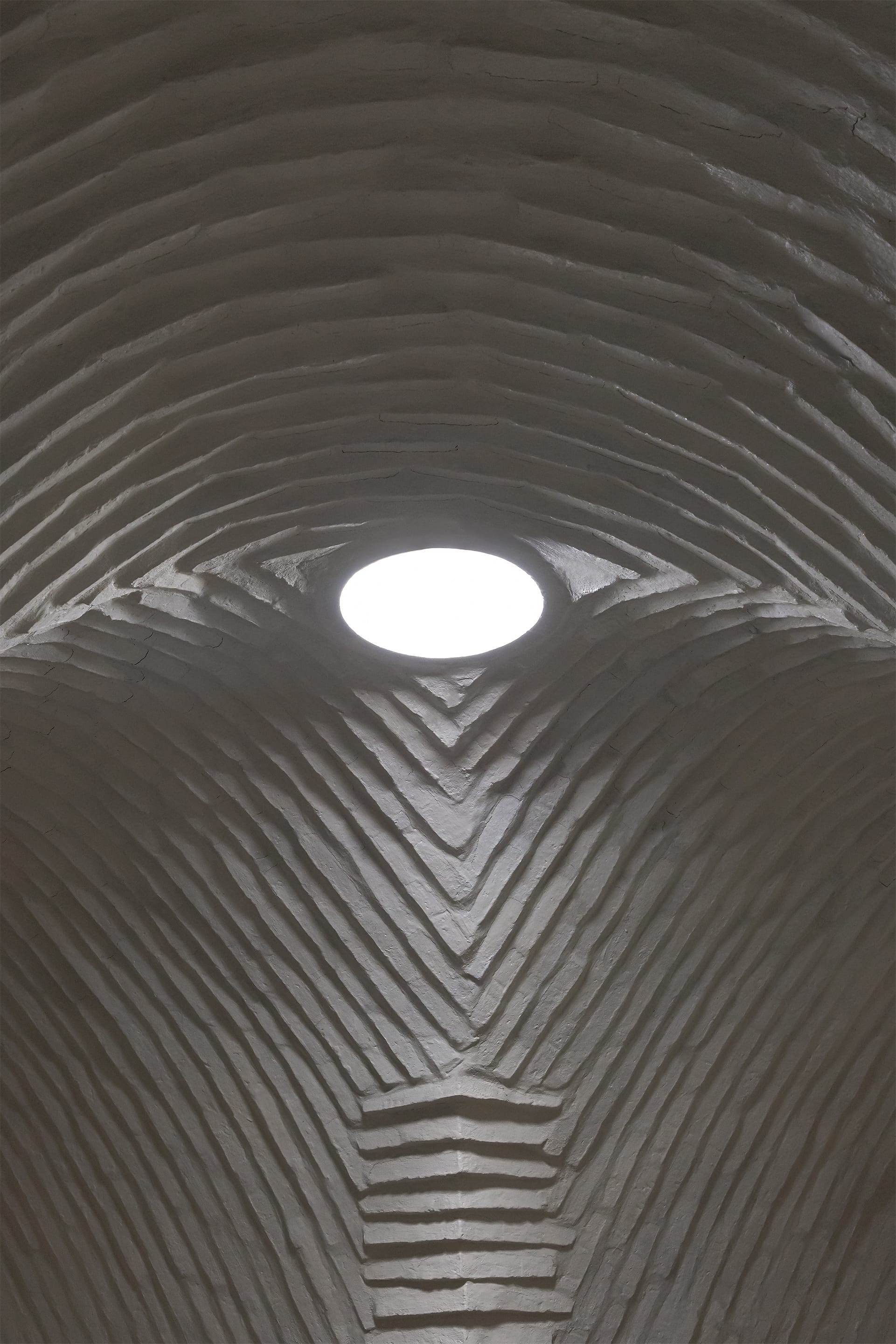 Specific, indigenous earth building brick technique interior ceiling with round top light.