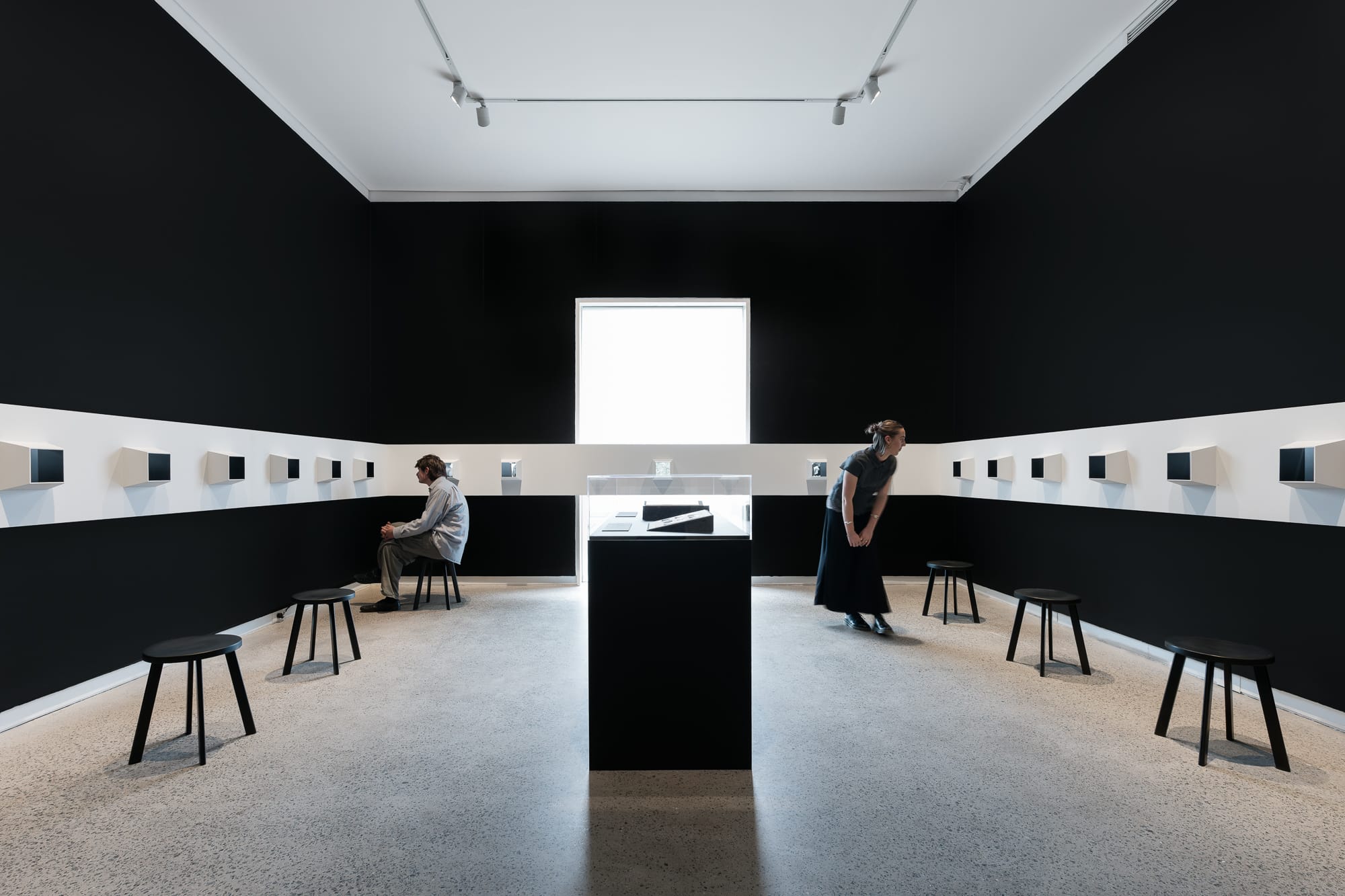 Black room with horizontal white stripe and view boxes and window.