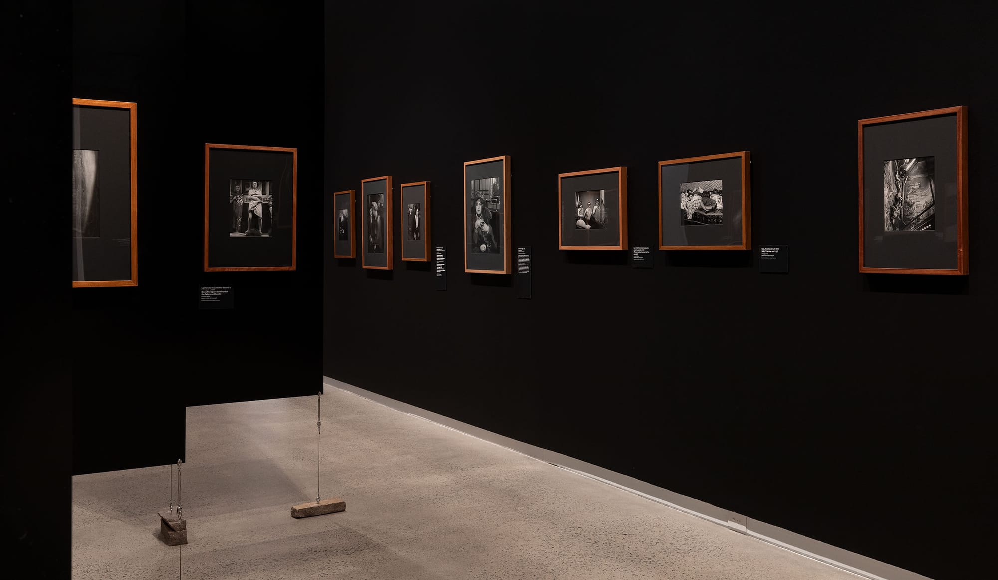 Black gallery space with wooden framed photographs.