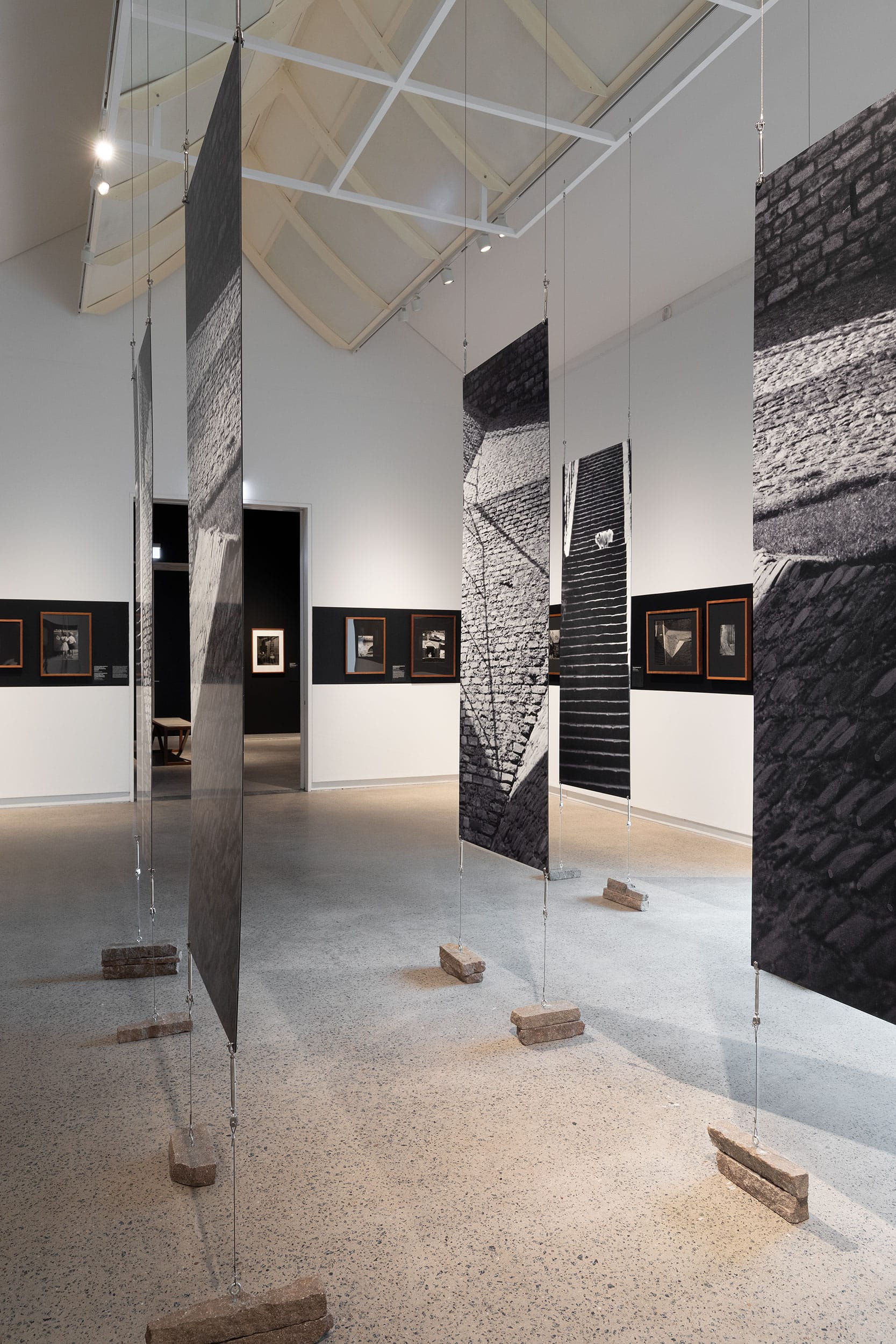 White gallery space showcasing photography and enlarged sectioned canvas in center.