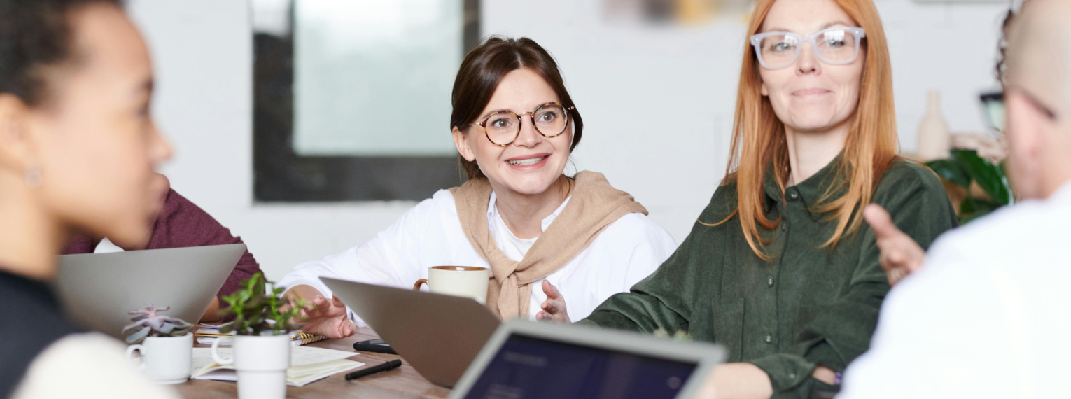 Mehrere Personen halten ein Arbeitsmeeting in einem Besprechungsraum.