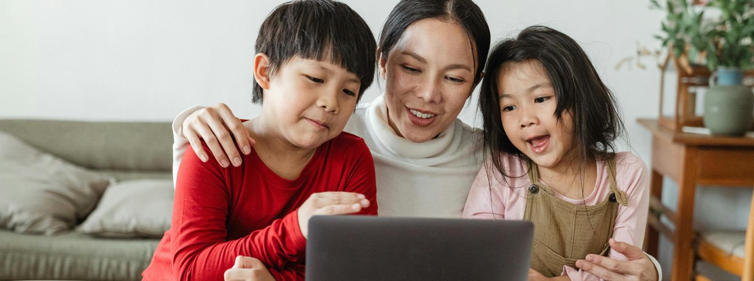 Eine Mutter schaut mit ihren Kindern auf einen Laptop.
