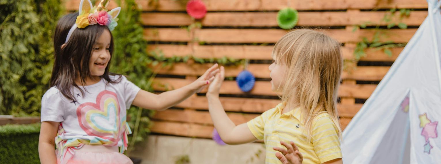 Zwei Mädchen spielen miteinander im Garten.