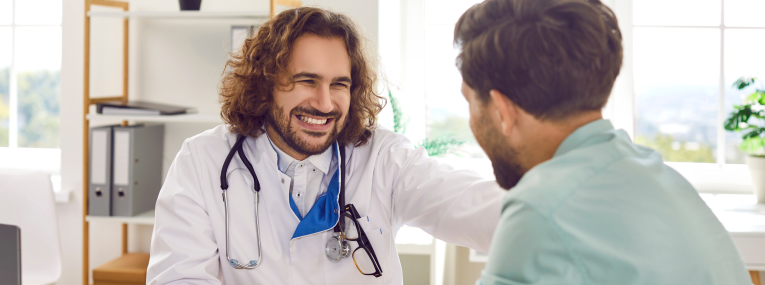 Ein Arzt lächelt einen Patienten nach einer Vorsorgeuntersuchung an.