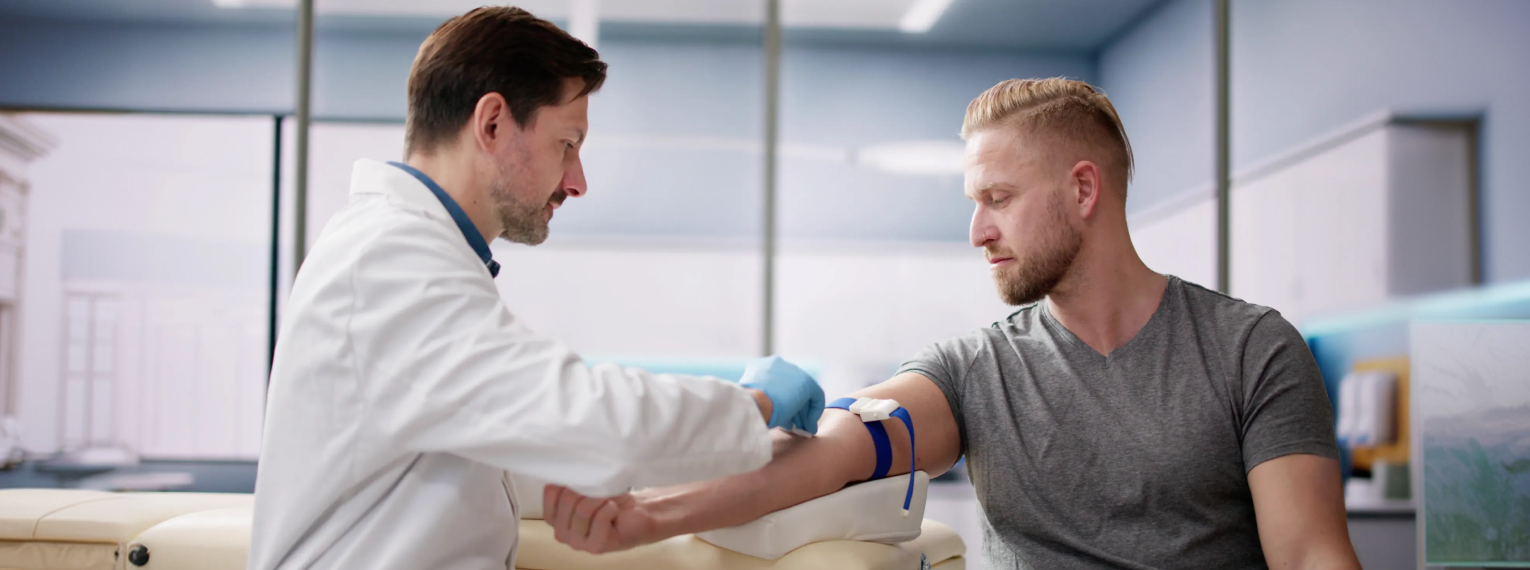 Ein Arzt nimmt seinem Patienten Blut ab.
