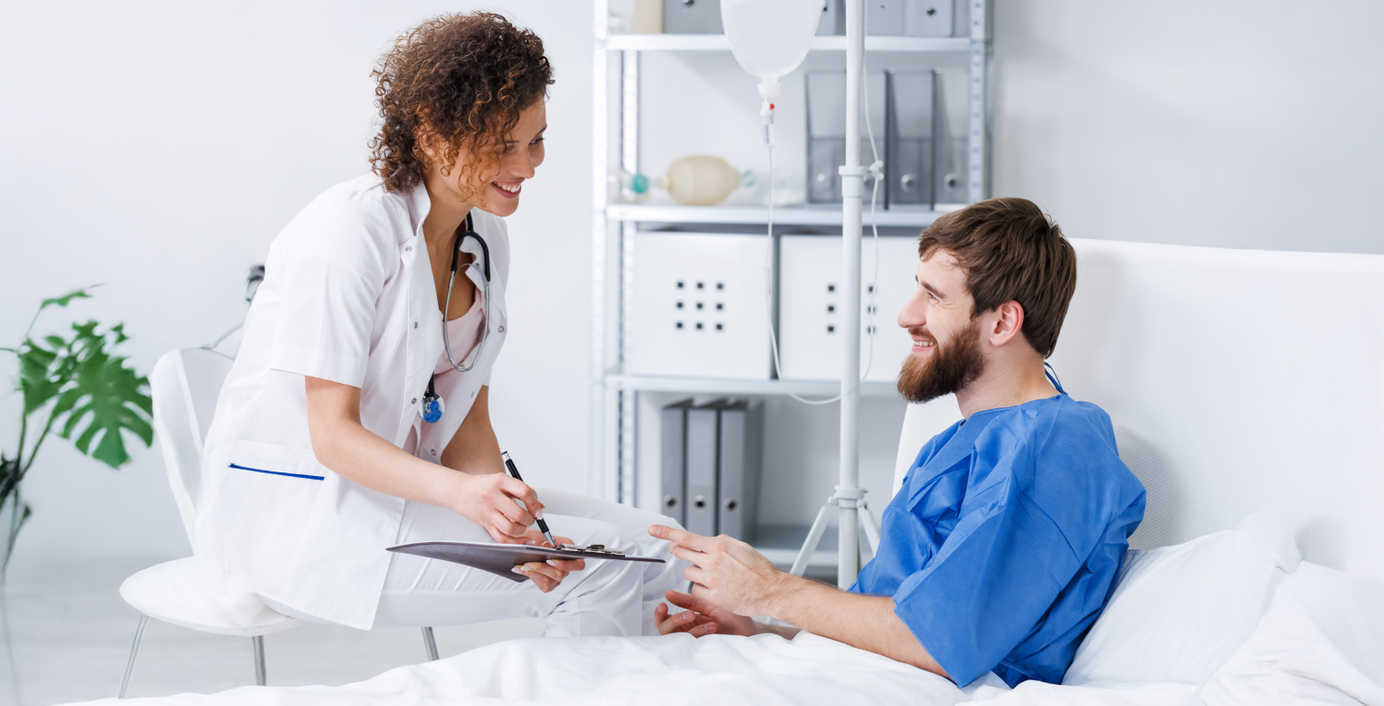 Ein Patient in einem Krankenhausbett spricht mit einer Ärztin.
