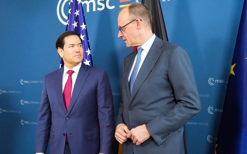 US Secretary of State Marco Rubio looks defiantly at Chancellor Merz in front of US, German and EU flags at the Munich Security Conference, February 2026.