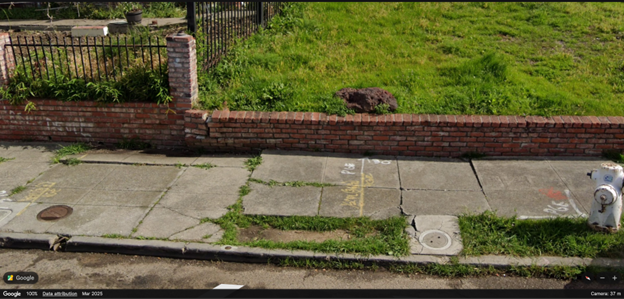 Image of cracked sidewalks with a short, crumbling brick wall.