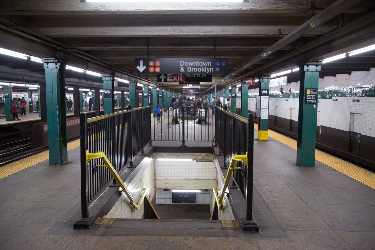 Subway platform. Stairs going down. Sign says downtown & Brooklyn.