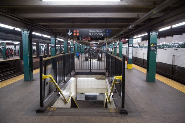 Subway platform. Stairs going down. Sign says downtown & Brooklyn.