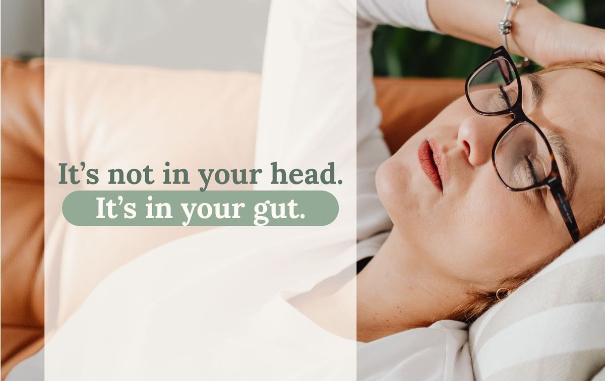 Woman lying on a sofa, wearing glasses, with one hand on her head