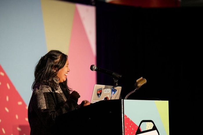 A speaker presenting at a colorful conference stage