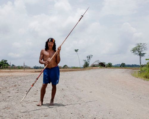 Davo Enomenga of the Waorani tribe in Yasuní, Ecuador. The Waorani hold legal rights to their land, but oil companies have been known to buy off communities with small gifts. Davo Enomenga controls a makeshift checkpoint where he keeps a traditional spear and a shotgun close at hand and demands gifts from anyone crossing his territory to reach oil.