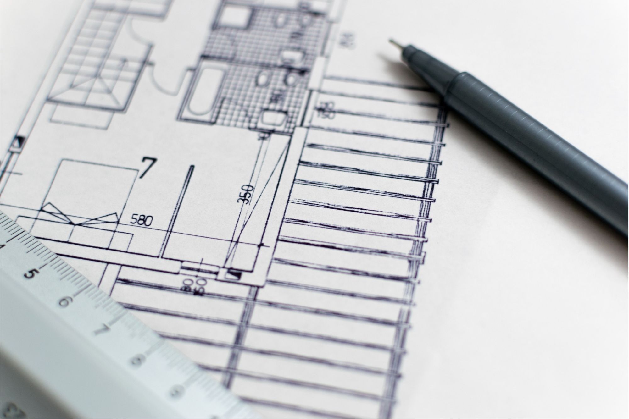 a blueprint for a new construction structure with a metal ruler and black pen on top