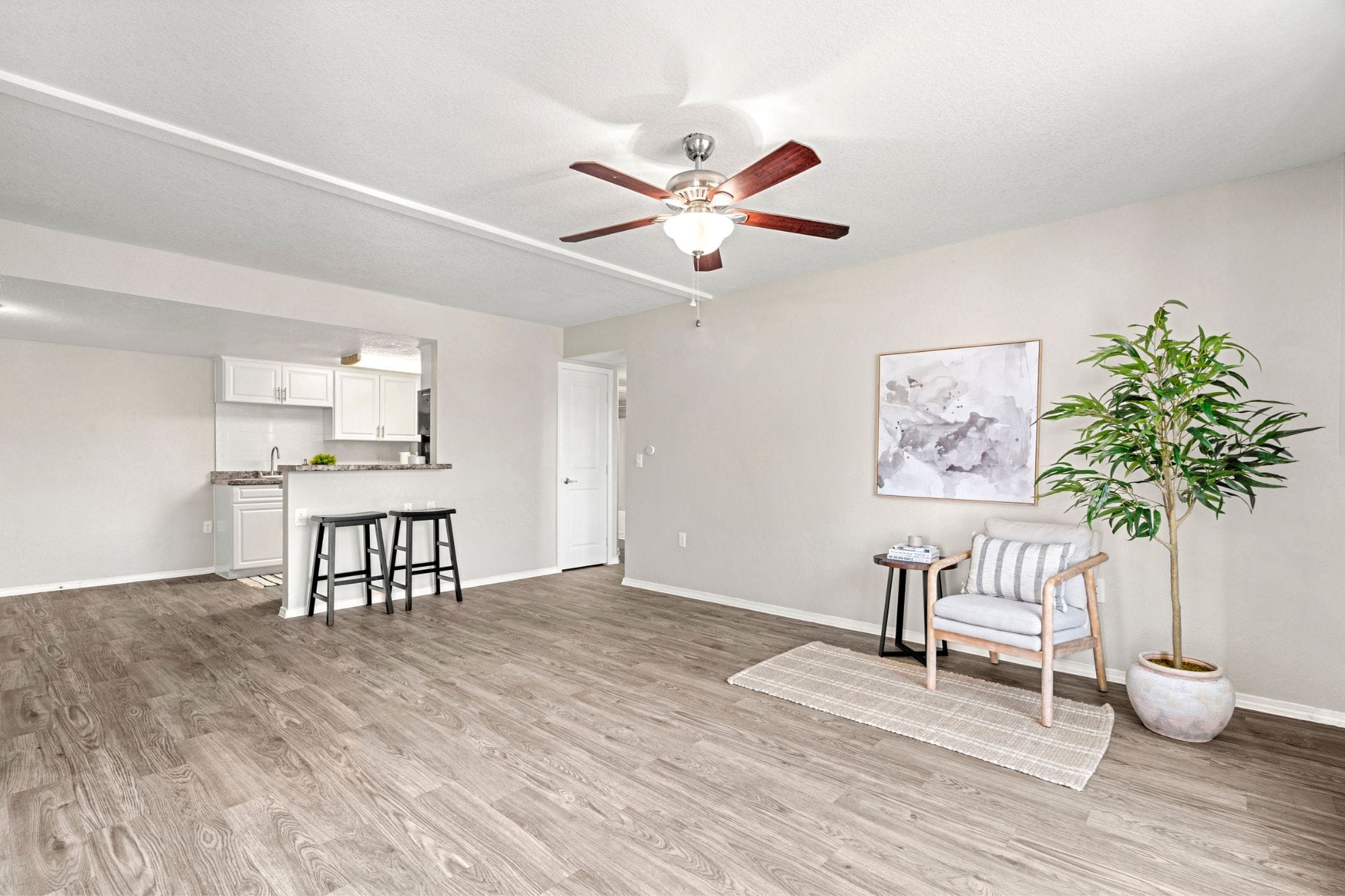 A large living room with ceiling fan, wood-style flooring, and breakfast bar connecting to the kitchen at Exchange on the 8 Apartments.