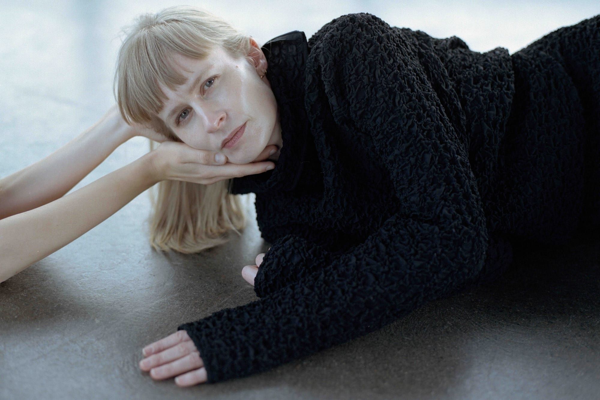 Jenny Hval laying on the floor with her head held up by two hand