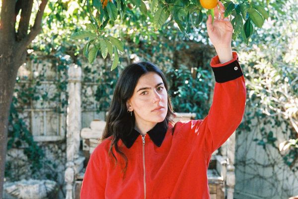 Avery Lynch in a red jacket beneath an orange tree