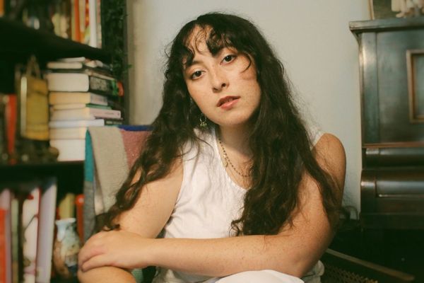 This photo shows the London-based singer/songwriter Ella Tobin in probably her home, with a bookshelf as backdrop, the artist