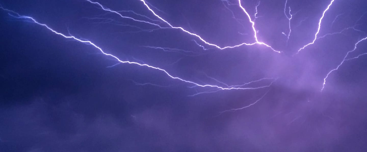 Clouds glow with purple lightning.
