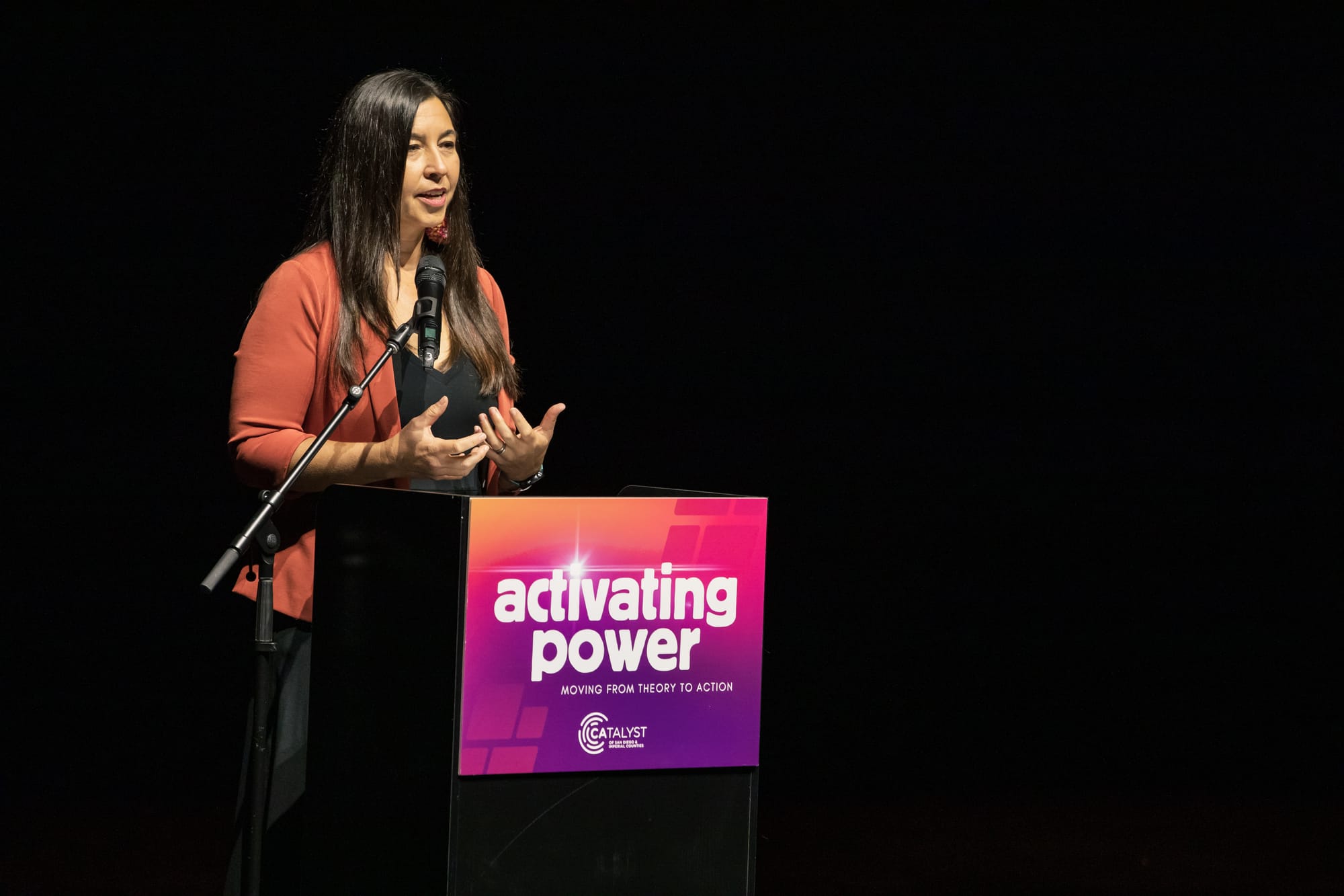 A woman stands at a podium with a sign that says activating power.