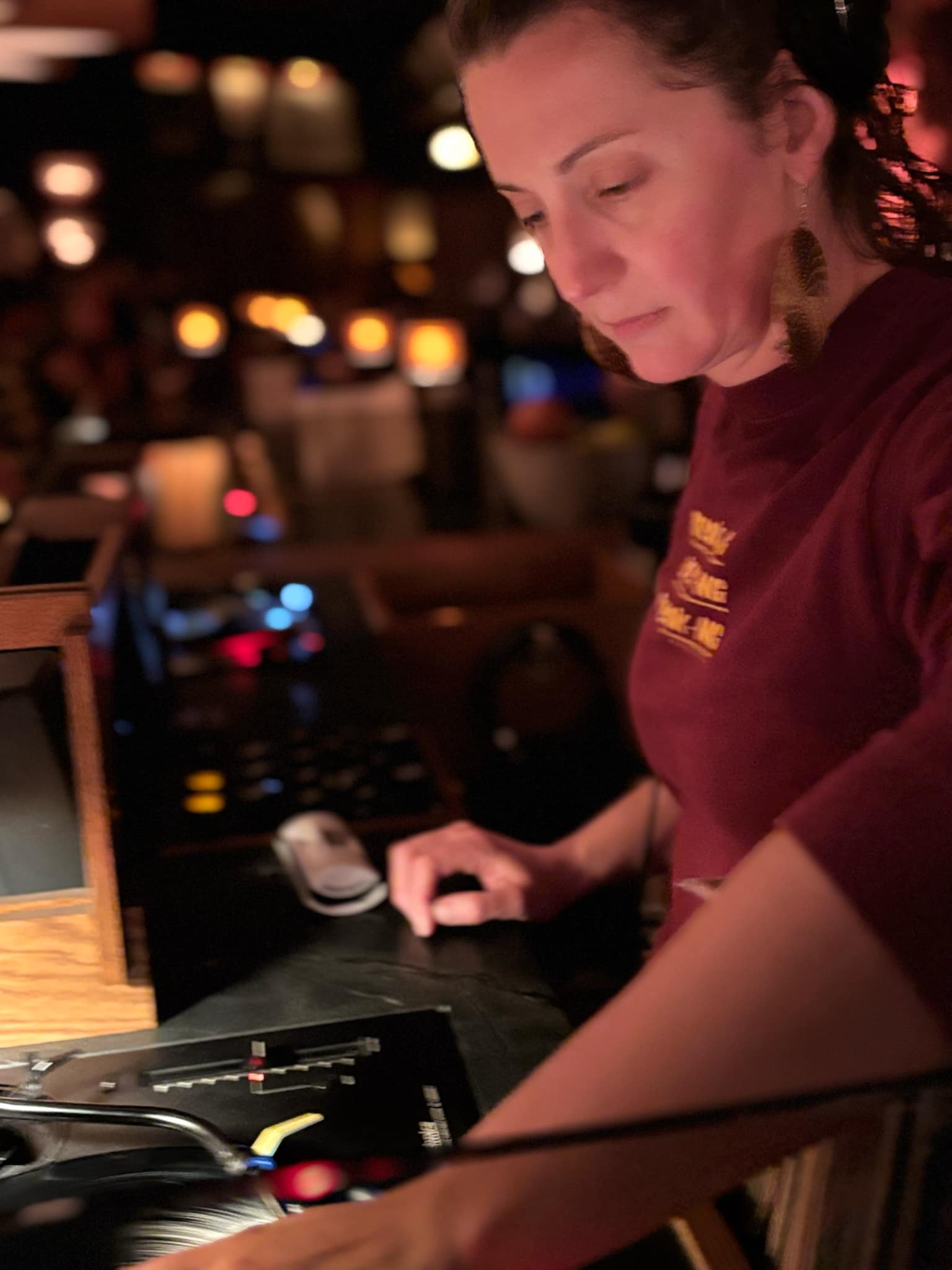 A woman spins records at a bar