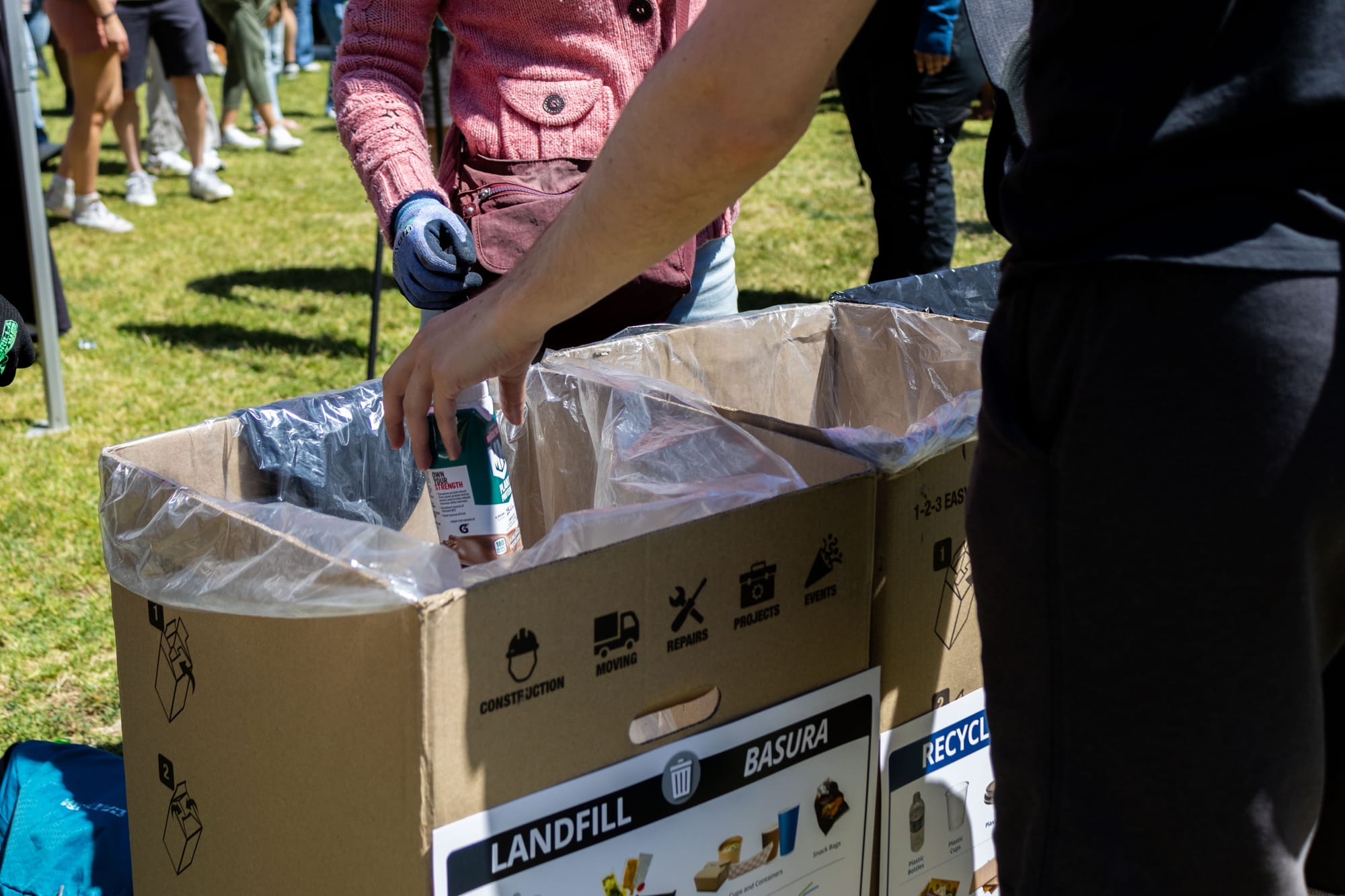 Close up of a landfill trash bin as someone throws away their garbage during an outdoor event